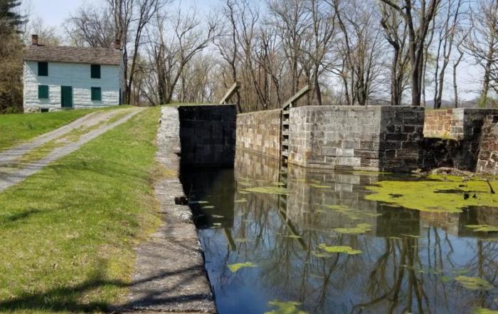 A small canal with a lock and a house in the background.