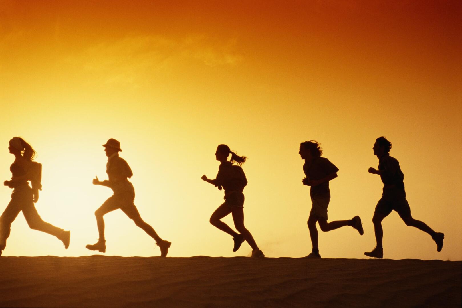 Silhouettes of people running at sunset.