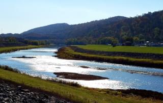 A river running through a grassy field with mountains in the background.