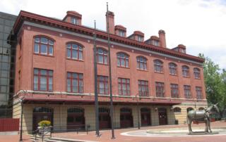 A large brick building with many windows and a balcony.